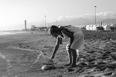 Girl touching dead jellyfish with a stick