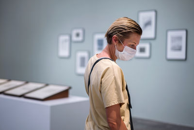 Side view of woman standing against wall