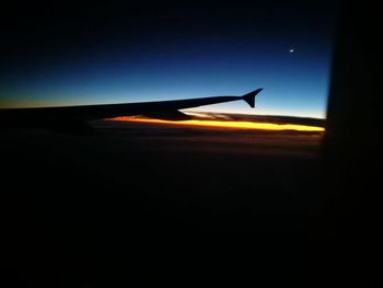 Silhouette airplane wing against sky during sunset