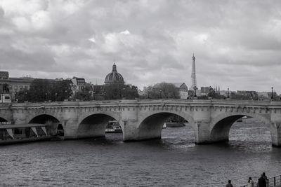Arch bridge over river against cloudy sky