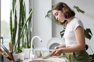 Side view of young woman holding potted plant