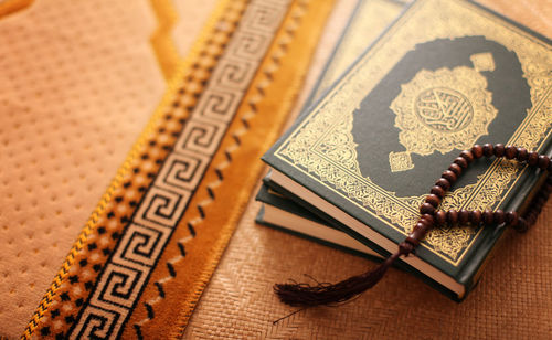 High angle view of koran and prayer beads on table