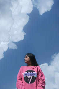 Portrait of young woman standing against sky