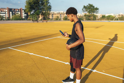 Side view african american sportsman in uniform looking at mobile