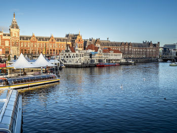 Buildings by river against clear sky