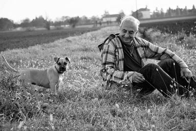 Portrait of man with dog sitting on field
