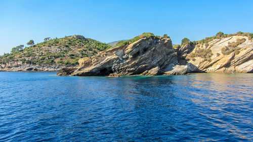 Scenic view of sea and mountains against clear blue sky