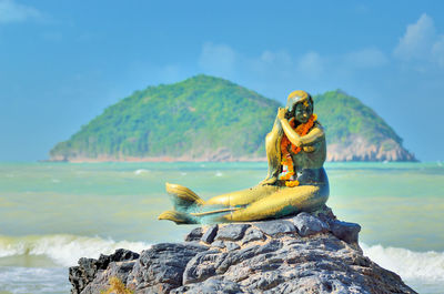 Close-up of statue on stone against beach