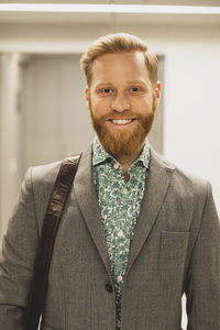 Bearded smiling businessman in corridor at office