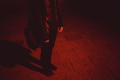 Low section of man standing with shadow on footpath at night
