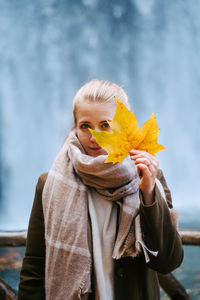 Portrait of woman holding yellow while standing outdoors