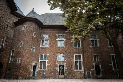 Low angle view of a man standing in the entrance of an old castle building against sky