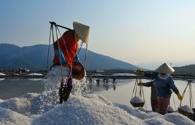 Woman working in salt flat against sky