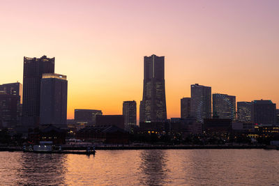 River amidst buildings against sky during sunset