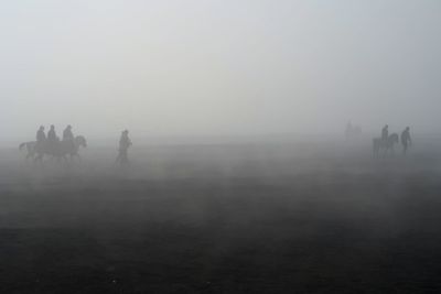 Silhouette people on snow covered land against sky