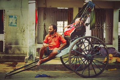 Full length portrait of woman sitting with bicycle