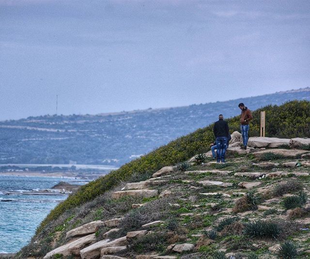 lifestyles, leisure activity, men, sea, water, sky, rear view, rock - object, nature, scenics, full length, beauty in nature, person, tranquil scene, tranquility, mountain, sitting