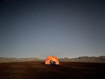 Rear view of woman with arms outstretched against sky at night