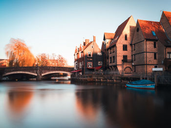 Buildings by river against sky at night