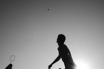 Low angle view of silhouette boy playing against clear sky