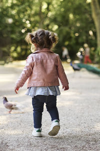 An 18 month old girl chasing a pigeon in a park