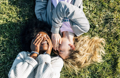 Two best friends telling secrets lying in the grass