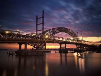 Bridge over river against sky at sunset