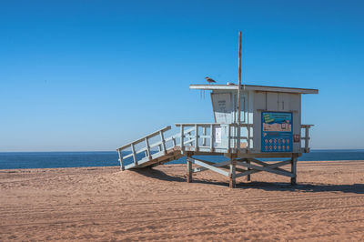 Lifeguard hut on beach against clear blue sky