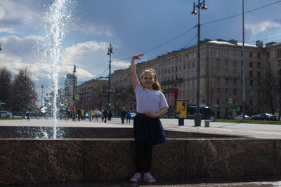 Happy little cute girl having fun in splashes a fountain