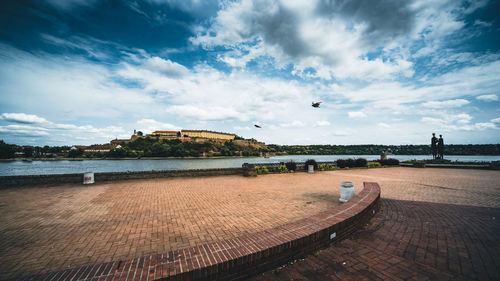 View of birds over river against cloudy sky