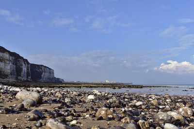 Stones at beach against blue sky