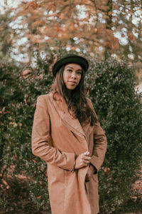 Portrait of young woman standing against plants during autumn