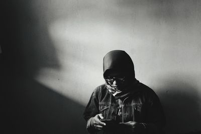 Portrait of young man standing against wall