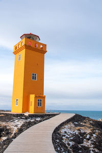 Lighthouse by sea against sky