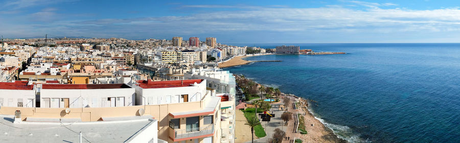 High angle view of town by sea against sky