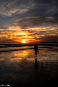 Silhouette man on beach against sky during sunset