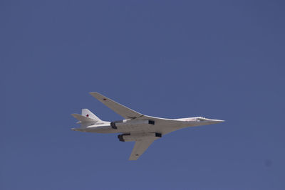 Low angle view of airplane flying against clear blue sky