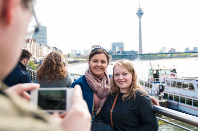 Portrait of smiling young woman using phone in city