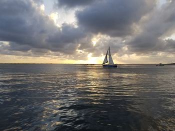 Sailboat in sea against sky during sunset