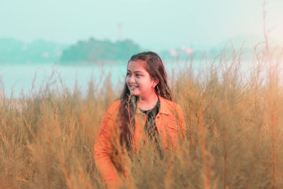 Portrait of young woman standing on field against sky