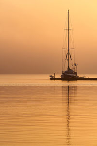 Sailboat sailing on sea against sky during sunset