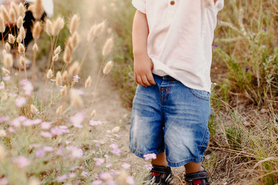 Midsection of boy standing against grassy land