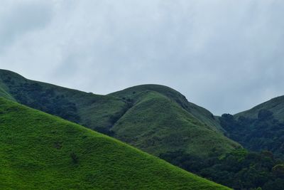 Low angle view of green mountain against sky