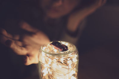 Close-up midsection of woman with toy car on mouth holding light in darkroom