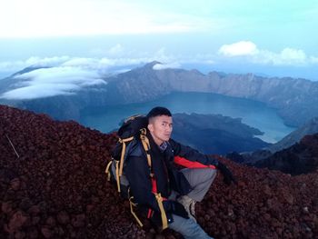 High angle portrait of young man sitting on mountain