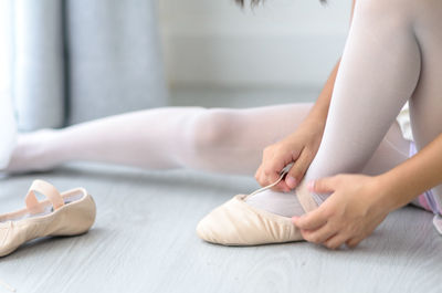 Low section of woman wearing ballet shoe