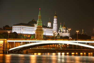 Illuminated bridge over river against sky in city at night