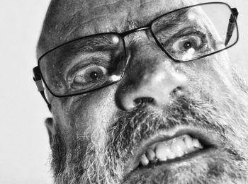 Close-up portrait of man wearing eyeglasses against gray background