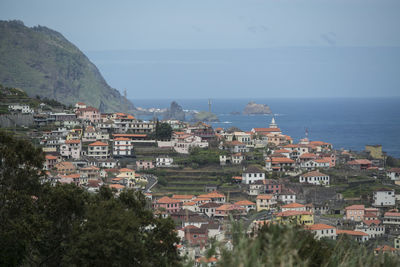 Aerial view of townscape by sea against sky