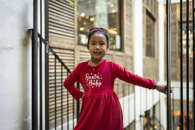 Portrait of young woman standing against building